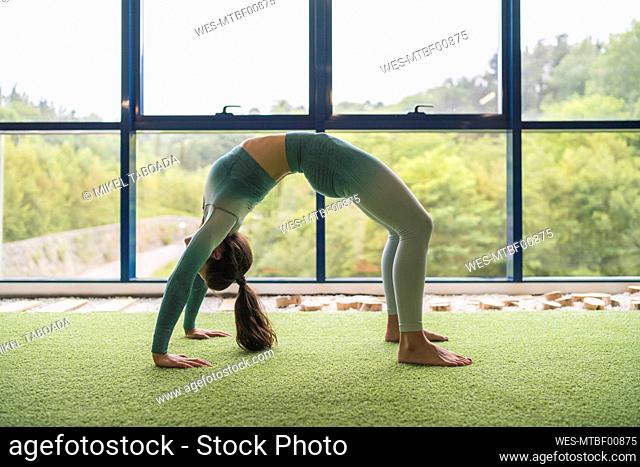 Sportswoman doing bending over exercise at gym