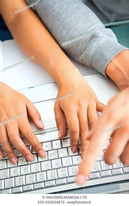 High view of students hands working with a laptop