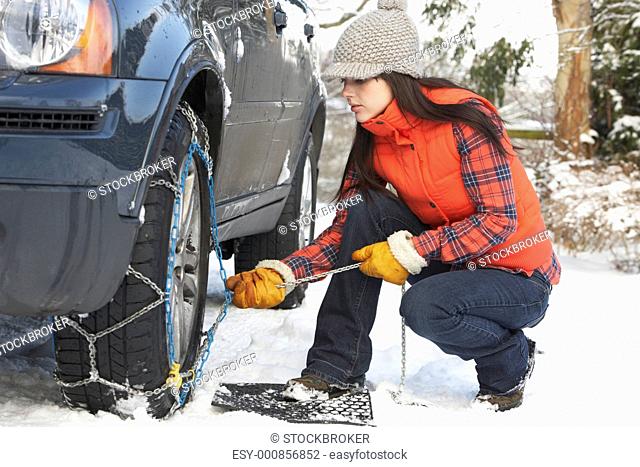 Woman Putting Snow Chains Onto Tyre Of Car