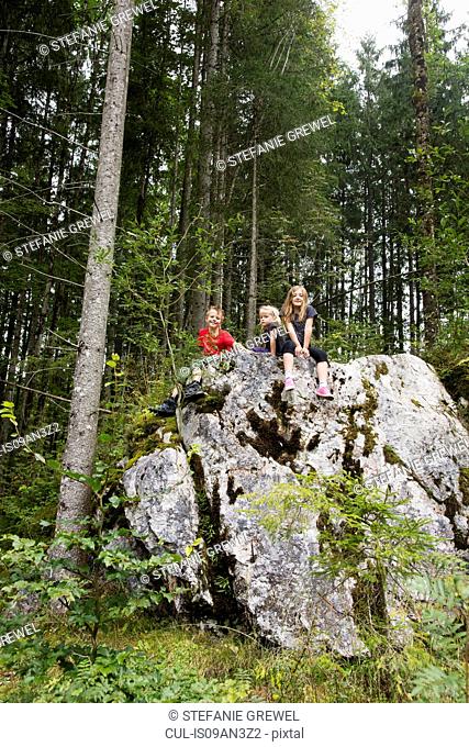 Brother and sisters playing on rock formation in forest, Zauberwald, Bavaria, Germany