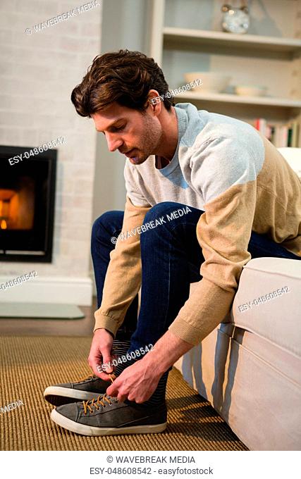 Man tying shoelaces in living room