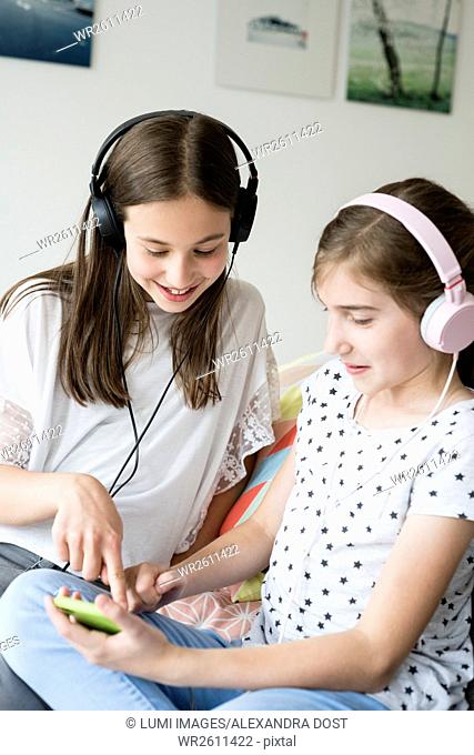 Two teenage girls with headphones listening to music