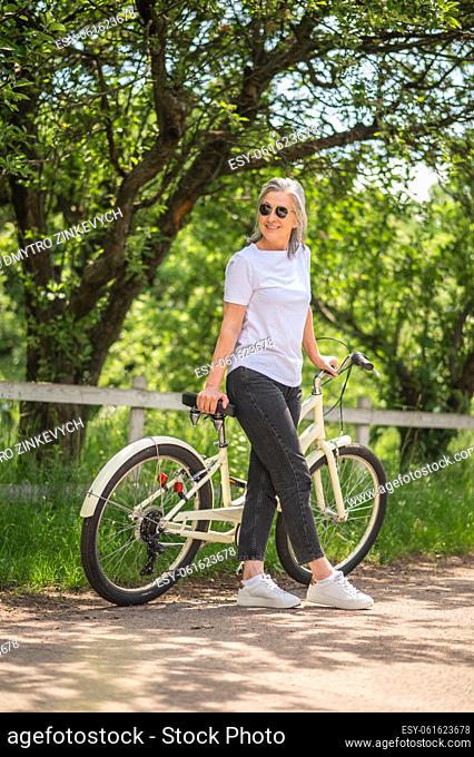 Digital detox. Active mture woman with a bike near in a countryside