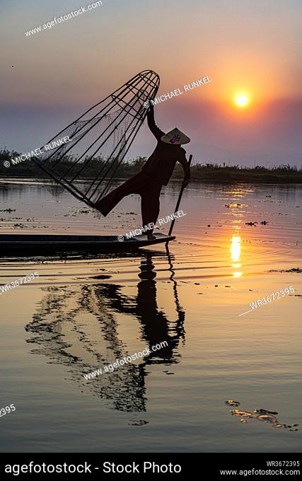 Myanmar,  Shan state, Silhouette of traditional Intha fisherman on Inle lake at sunset