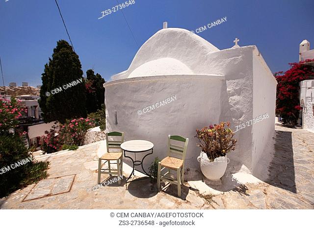 Tables and chairs of a restaurant in front of a whitewashed chapel in the old town Chora, Amorgos, Cyclades Islands, Greek Islands, Greece, Europe