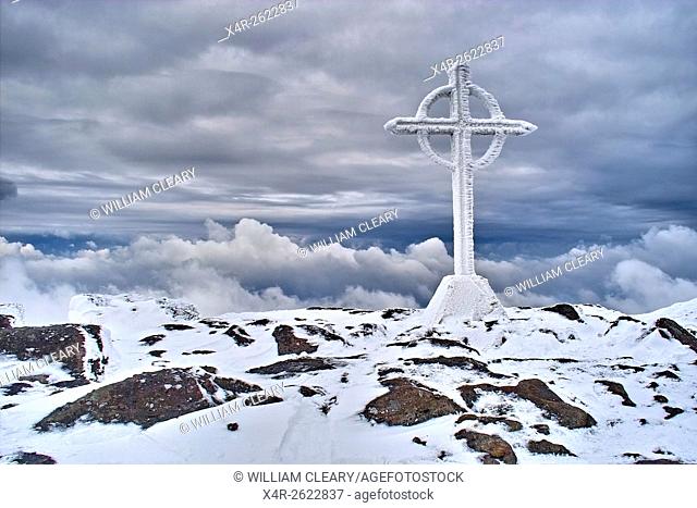The summit cross on the snow covered summit of Galtymore, Galtee Mountains, County Tipperary, Ireland