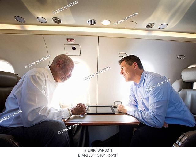 Businessmen talking on airplane