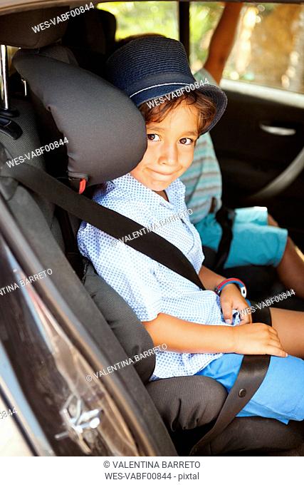 Portrait of smiling little boy sitting on backseat of a car