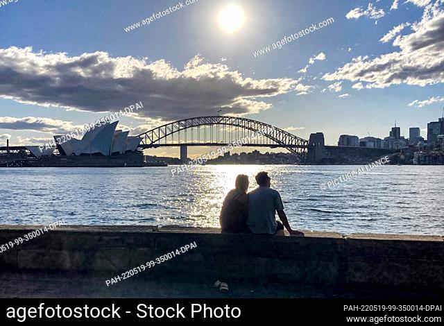 PRODUCTION - 17 May 2022, Australia, Sydney: A couple looks out over the Harbour Bridge and the Sydney Opera House. Who will win the race in the upcoming...