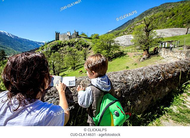 Consultation of an information leaflet on the trail to Castle Visconti Venosta, Grosio, Valtellina, Lombardy, Italy, Europe