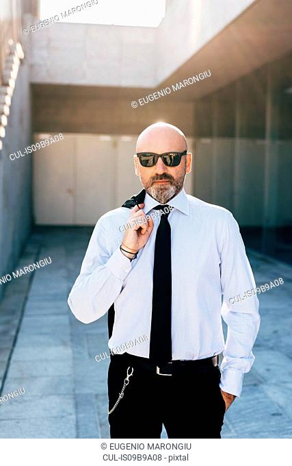 Portrait of mature businessman outdoors, carrying jacket over shoulder