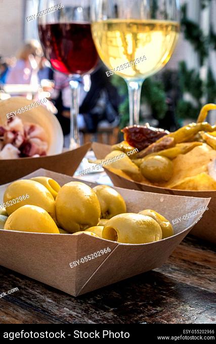 Snacks and wine in a tapas bar. Olives and pinchos with wineglasses in an outdoors cafe