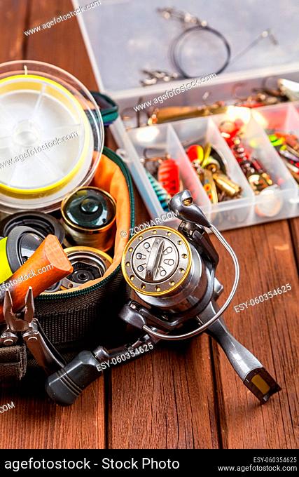 Different fishing tacles with lures and reels on wooden brown background with place for text. Design for advertisment and publishing