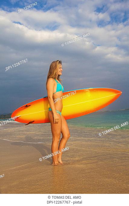 Teenage girl with her surfboard; Kailua, Island of Hawaii, Hawaii, United States of America