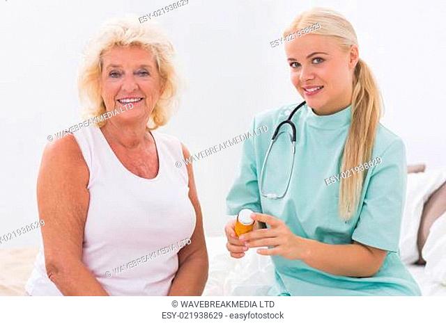 Home nurse showing a pill bottle to her patient