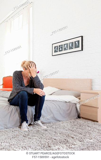 Woman sitting on the edge of her bed with a headache