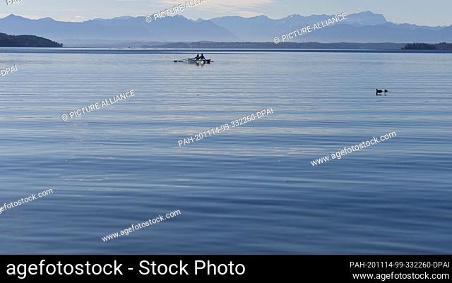 14 November 2020, Bavaria, Starnberg: Rowers are on their way on the Starnberger See, in the background the Wetterstein mountain range with the Zugspitze (r)...