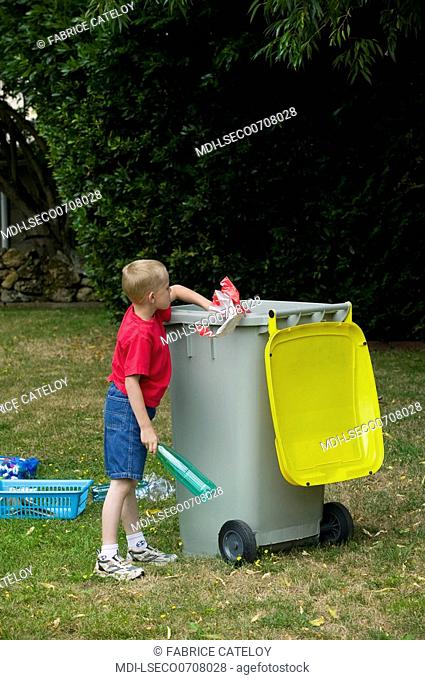 Young boy selecting waste in recycling container