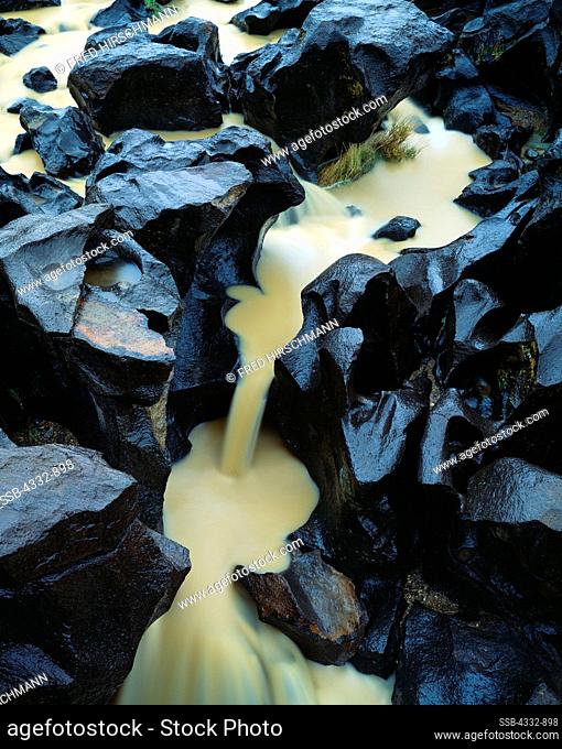 Silty water from recent rain flowing over fluted basalt at Fossil Falls, a Bureau of Land Management Geological Area preserving the site of a major river...