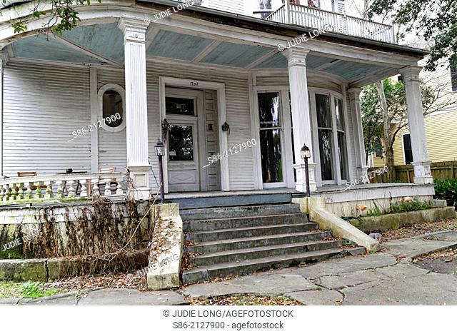 Dilapidated Front Porch and Yard on an Old Home in the Garden District of New Orleans, Louisiana, USA