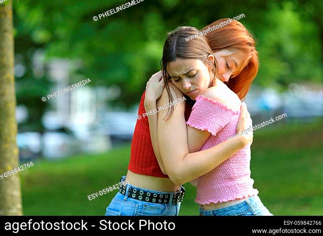 Sad women reconciling hugging in a green park