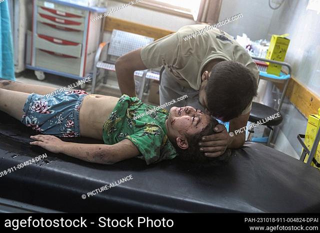 18 October 2023, Palestinian Territories, Khan Yunis: A man comforts an injured child while receiving treatment at a Nasser Hospital after air strikes at the...