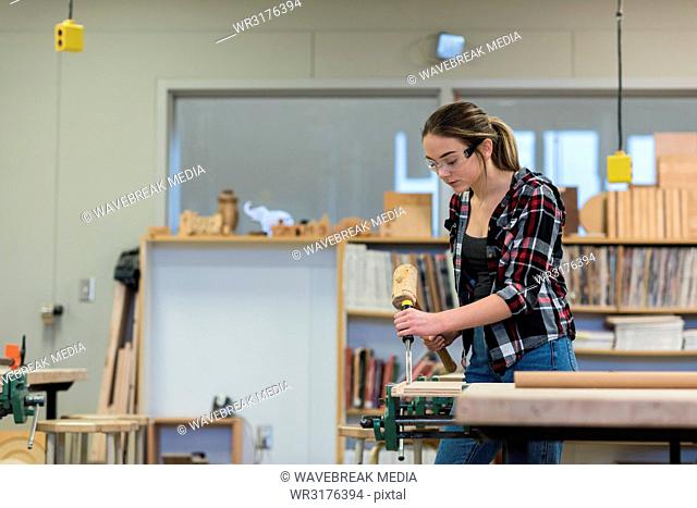 Female carpenter using chisel with hammer on a piece of wood