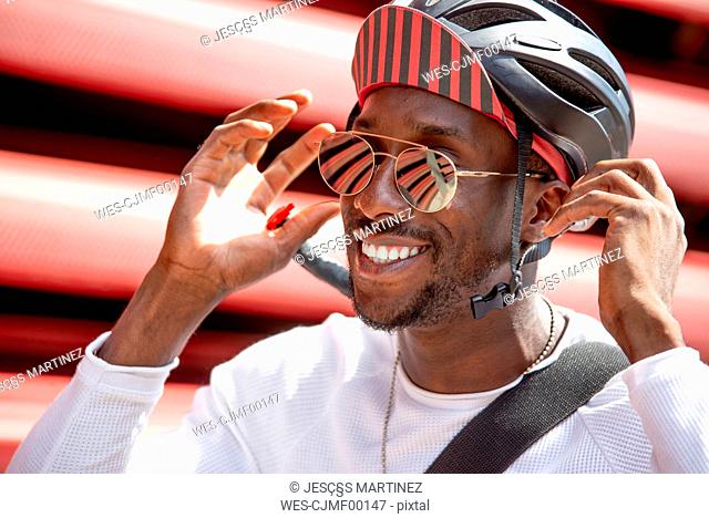 Smiling young man putting on his cycling helmet