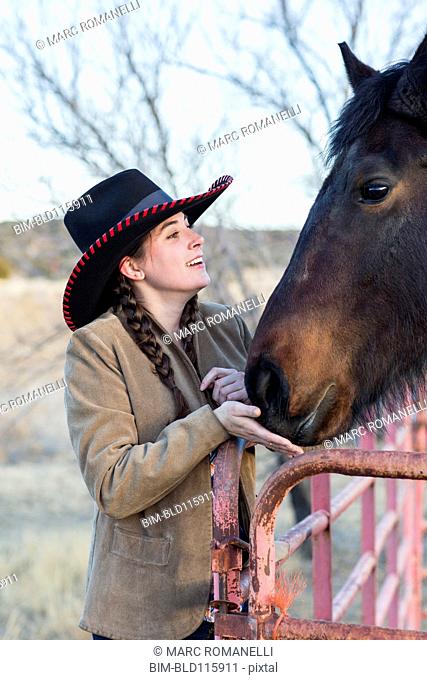 Caucasian girl petting horse on farm