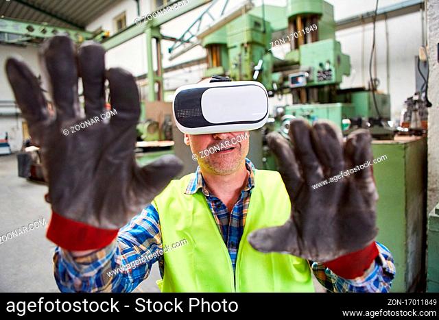 Arbeiter mit VR-Brille greift mit Händen bei Virtual Reality Simulation der Fabrik der Zukunft