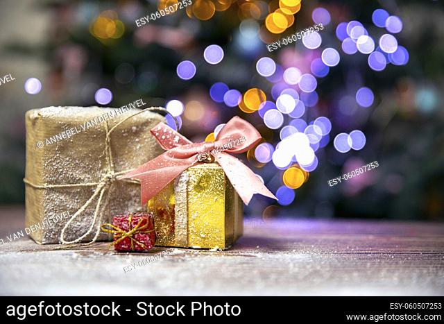 Merry Christmas, New Year, gifts in gold boxes with pink bow in the snow, bokeh Christmas tree background with copy space, Holiday