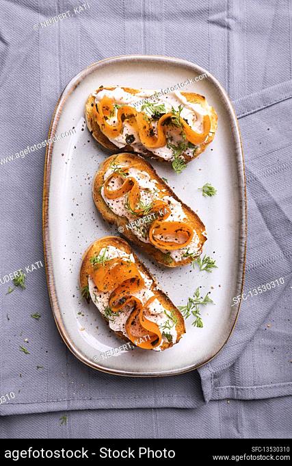 Toasted baguette slices with almond cream, vegan carrot salmon and dill