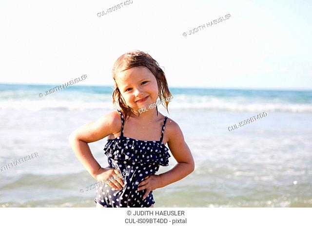 Cute girl on beach in spotted swimming costume, portrait, Castellammare del Golfo, Sicily, Italy