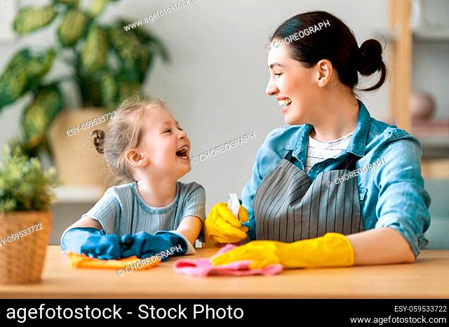 Happy family at home. Mother and daughter doing the cleaning in the house. A young woman and child girl are dusting. Cute little helper