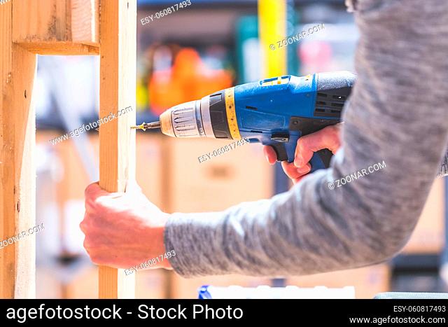 Do it yourself home handyman is using a cordless screwdriver for screwing