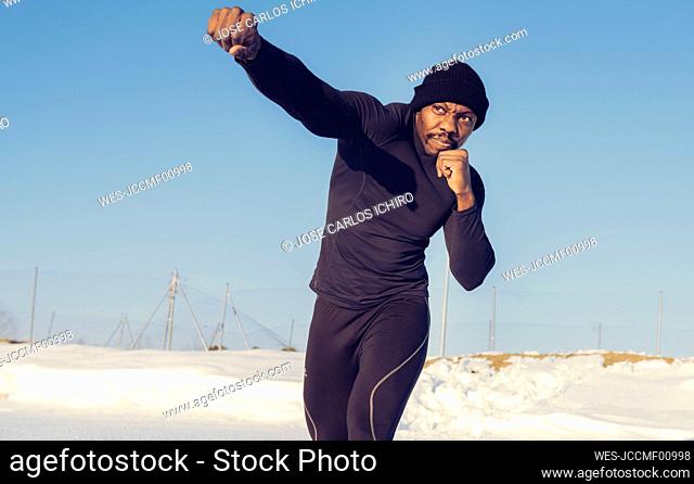 Sportsman practicing boxing while standing against sky