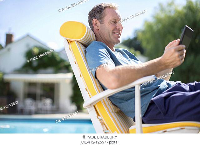 Man reading in lounge chair at poolside