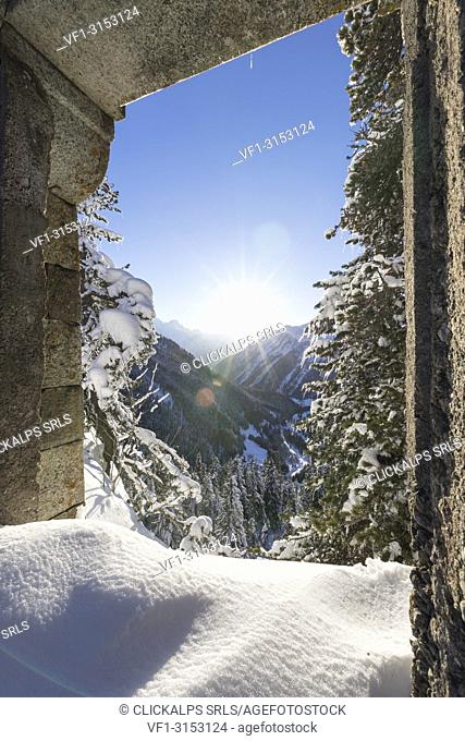 Bregaglia Valley seen from open stone arch surrounded by snow, Maloja Pass, canton of Graubunden, Engadin, Switzerland