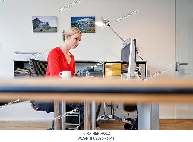 Young woman working on computer at desk in office