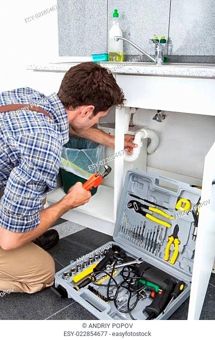 Plumber Fixing Sink In Kitchen