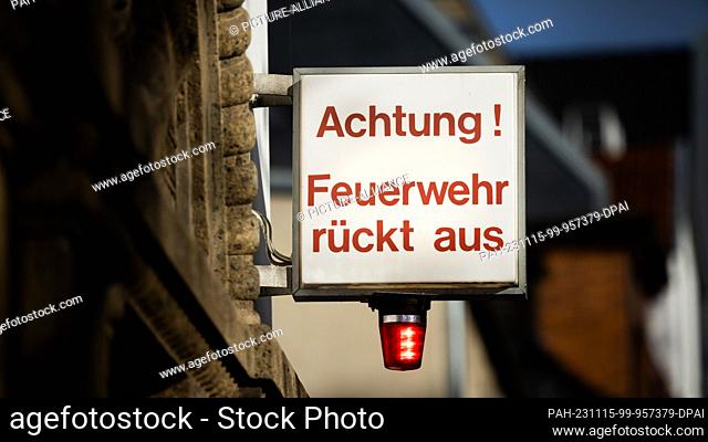 15 November 2023, North Rhine-Westphalia, Cologne: ""Attention! Fire department moving out"" and a light shine at a fire station to indicate an imminent...