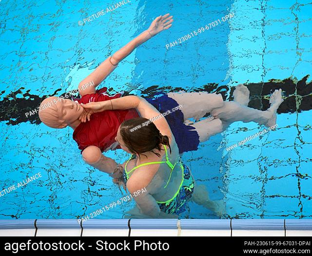 14 June 2023, Berlin: A young woman demonstrates the procedure for rescuing a casualty on a mannequin during the pre-swim of potential lifeguards at the...