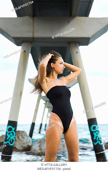 Beautiful young woman wearing swimsuit standing at the seafront