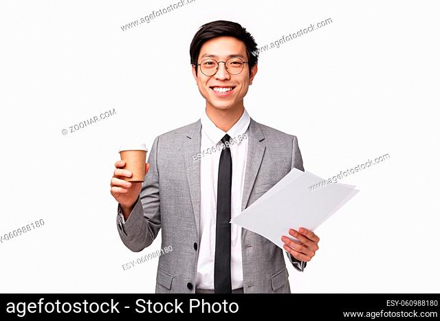 Office workers, business and lifestyle concept. Waist-up portrait of upbeat, enthusiastic young asian businessman drinking morning coffee at office