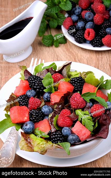 Fruit salad with blackberry, raspberry, blueberry, watermelon slices and mix of green leaves