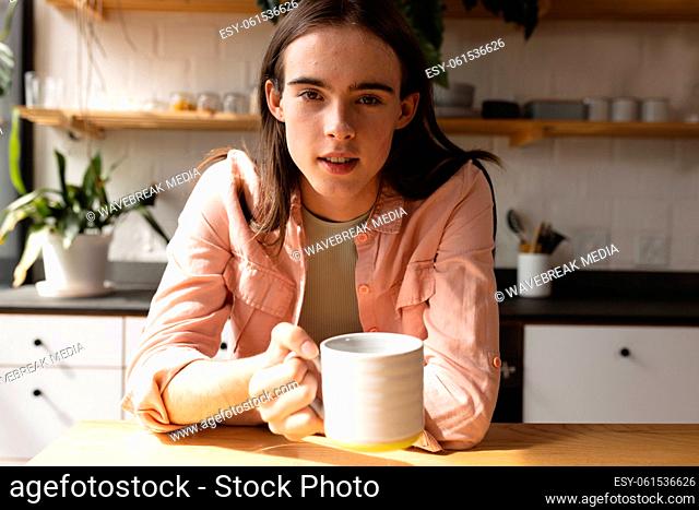 Portrait of non-binary trans woman holding a coffee cup in the kitchen at home