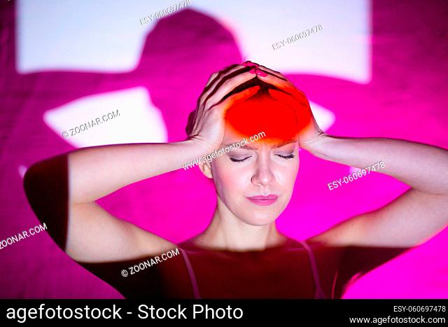 Young woman with headache and red color forehead