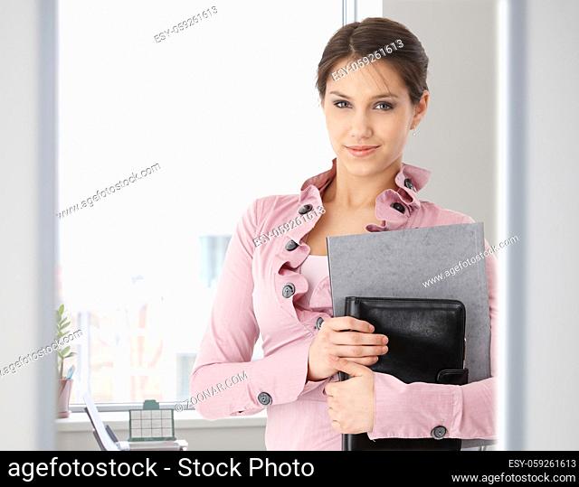 Portrait of young caucasian office worker standing. looking at camera, smiling