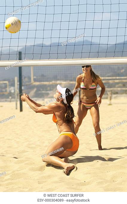 Beach volleyball player diving for volleyball near net