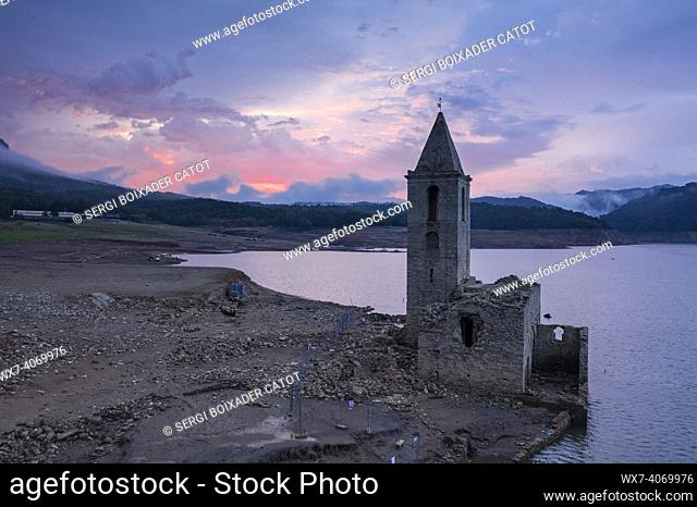 Bell tower of Sau fully exposed during the drought of 2022. Red sunrise in the swamp (Osona, Barcelona, Catalonia, Spain)